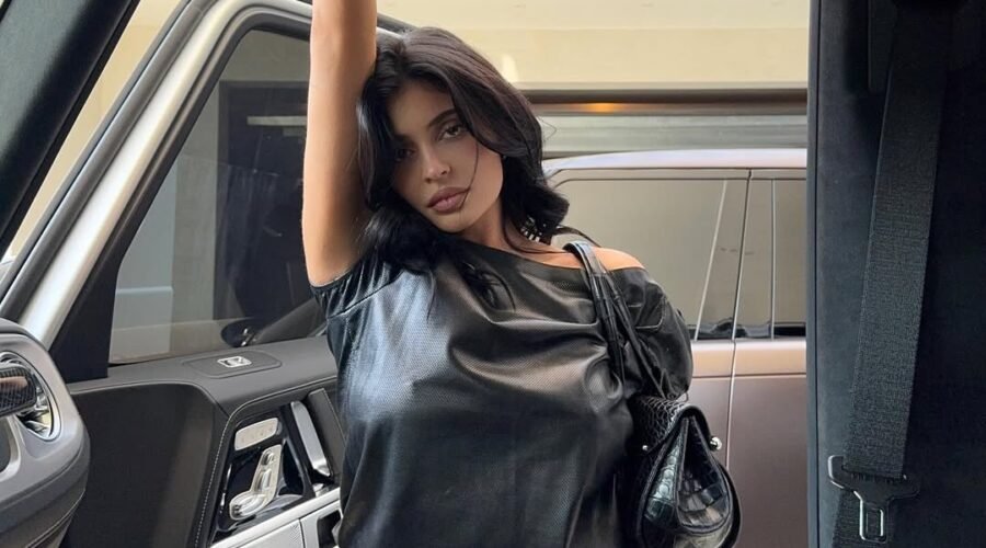 Kylie Jenner standing on a car door